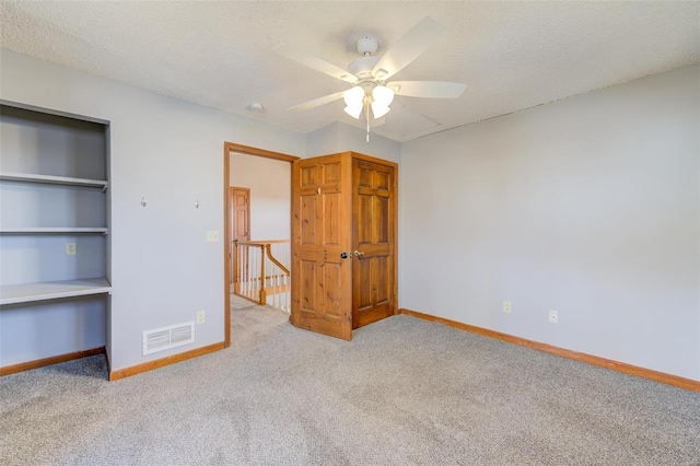 unfurnished bedroom featuring ceiling fan, light colored carpet, and a textured ceiling