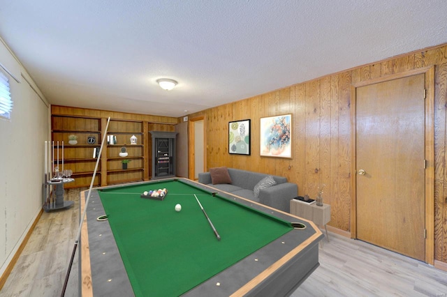 recreation room featuring wood walls, light wood-type flooring, a textured ceiling, and billiards