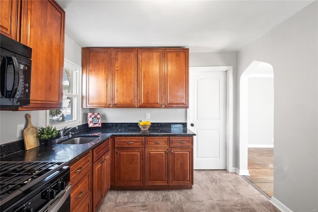 kitchen with sink, gas range oven, and dark stone counters