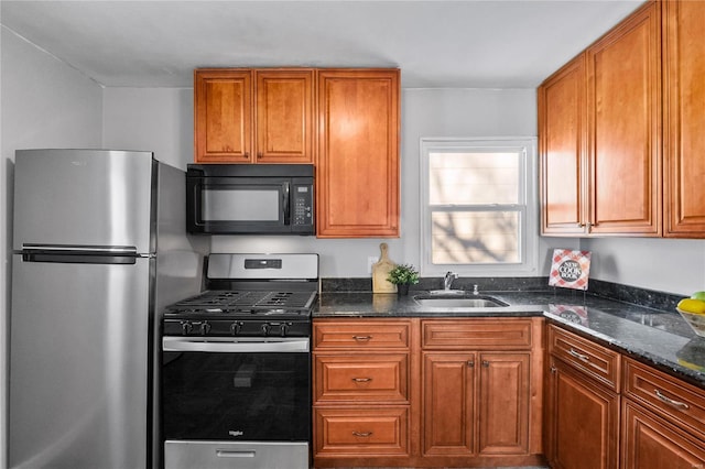 kitchen with stainless steel appliances, dark stone counters, and sink