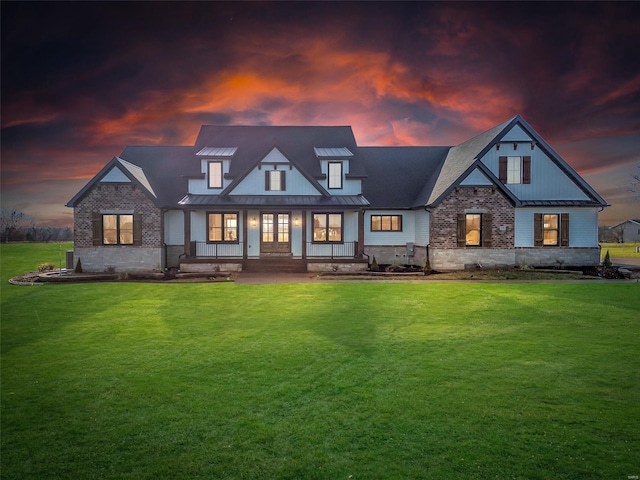 back house at dusk with a porch and a lawn