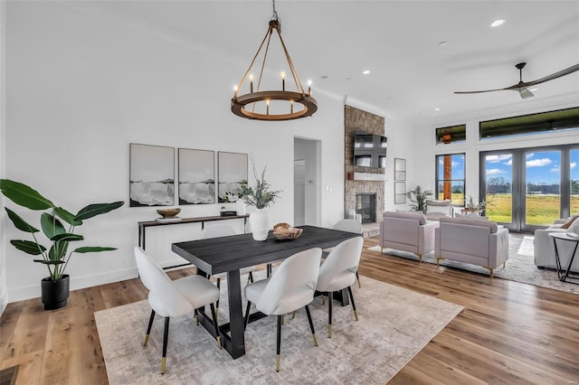 dining area with ceiling fan with notable chandelier, light wood-type flooring, and a fireplace