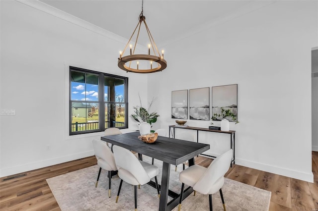 dining area with crown molding, a chandelier, and hardwood / wood-style flooring