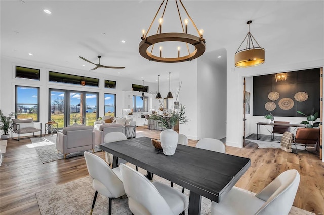 dining space with ceiling fan with notable chandelier, light wood-type flooring, and french doors