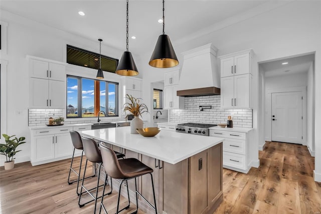 kitchen with premium range hood, tasteful backsplash, white cabinets, and a kitchen island