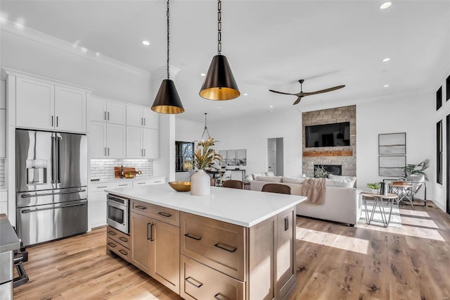 kitchen featuring tasteful backsplash, high end fridge, white cabinets, a center island, and hanging light fixtures