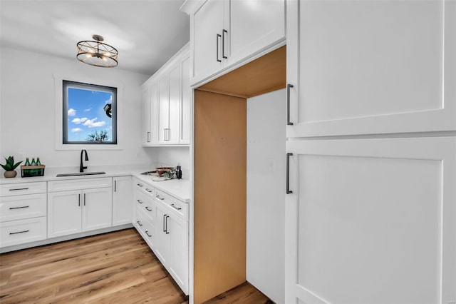 kitchen with sink, white cabinets, and light hardwood / wood-style floors