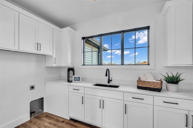 washroom with hardwood / wood-style floors, electric dryer hookup, cabinets, and sink