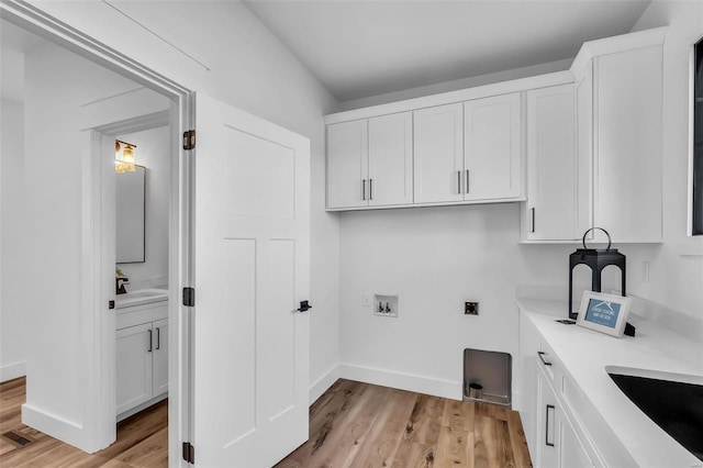 washroom featuring cabinets, sink, hookup for a washing machine, light wood-type flooring, and hookup for an electric dryer