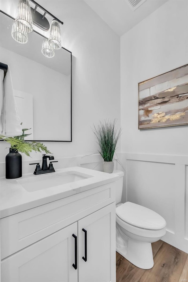 bathroom featuring hardwood / wood-style flooring, vanity, a chandelier, and toilet