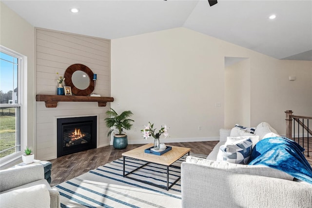 living room featuring dark hardwood / wood-style floors, a large fireplace, and vaulted ceiling