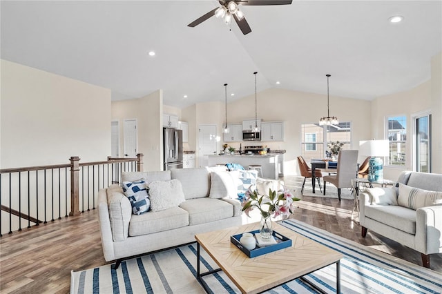 living room featuring lofted ceiling, light hardwood / wood-style flooring, and ceiling fan with notable chandelier