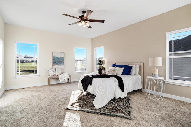 bedroom with multiple windows, ceiling fan, and carpet