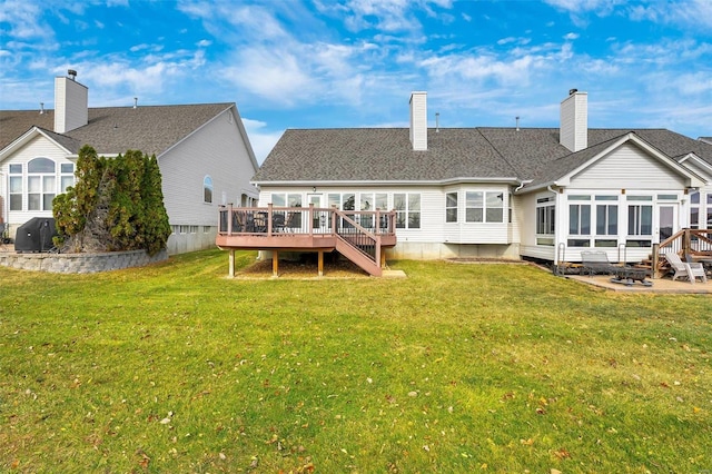 back of property featuring a sunroom, a lawn, and a wooden deck