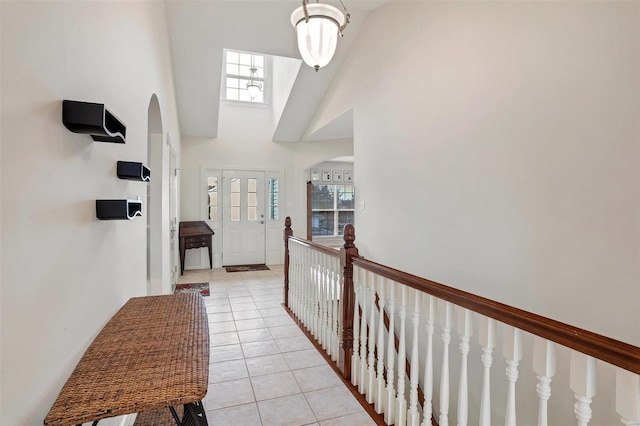 hallway featuring a towering ceiling and light tile patterned flooring