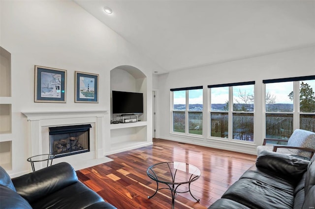 living room with built in features, vaulted ceiling, and hardwood / wood-style flooring