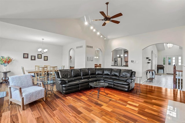 living room with ceiling fan with notable chandelier, light hardwood / wood-style floors, high vaulted ceiling, and french doors