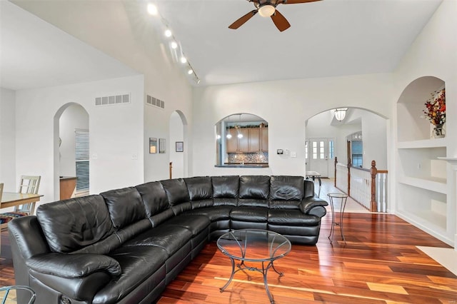 living room featuring built in shelves, ceiling fan, and wood-type flooring