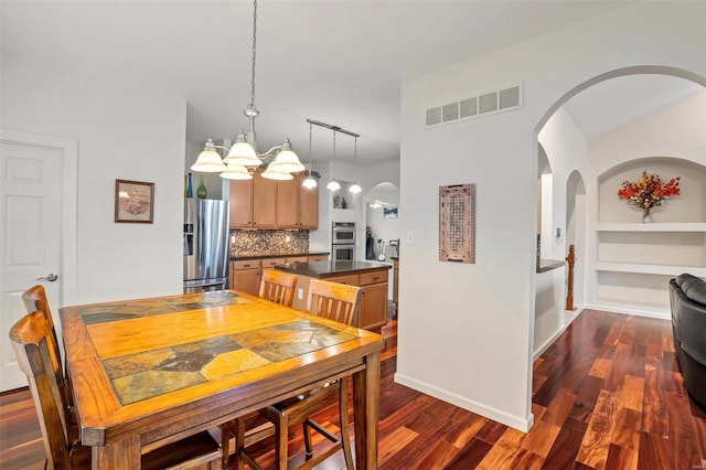 dining room featuring a chandelier, built in shelves, and dark hardwood / wood-style floors