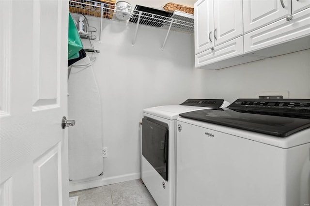 clothes washing area featuring washing machine and dryer, light tile patterned floors, and cabinets