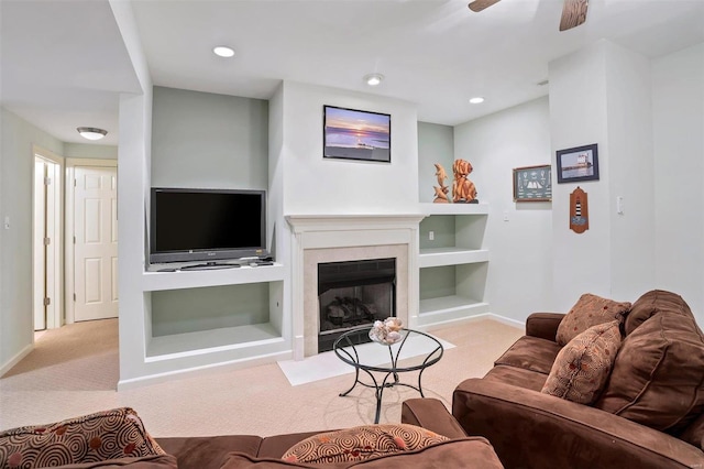 living room with ceiling fan, light colored carpet, and built in features