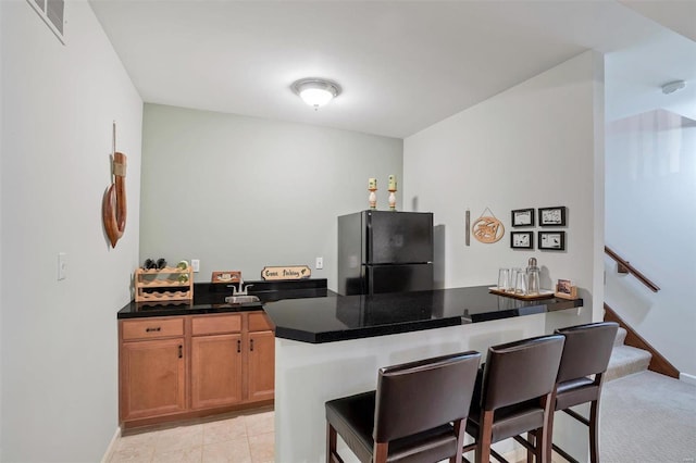 kitchen featuring a kitchen bar, kitchen peninsula, and black refrigerator