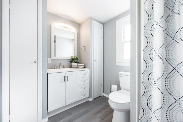 bathroom with hardwood / wood-style floors, vanity, toilet, and walk in shower