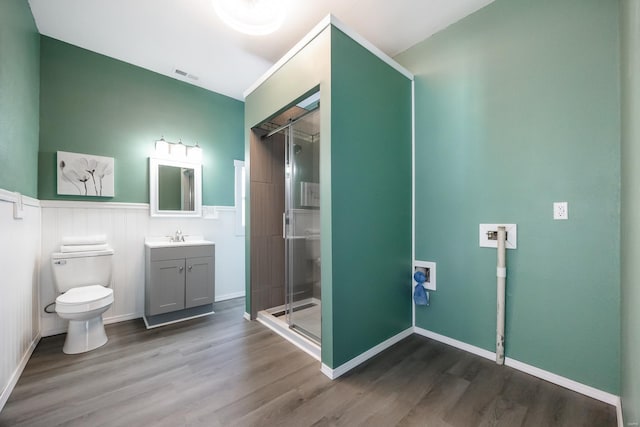 bathroom with hardwood / wood-style floors, vanity, toilet, and a shower with shower door