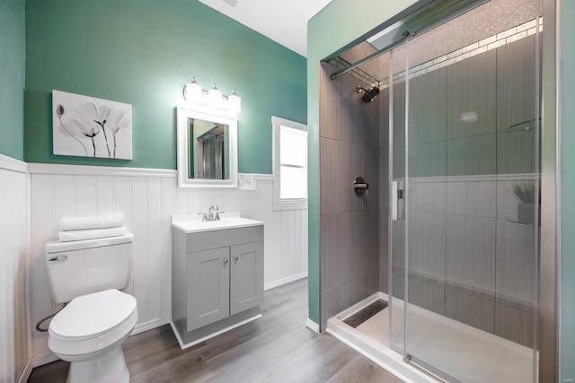 bathroom with a shower with door, vanity, hardwood / wood-style floors, and toilet