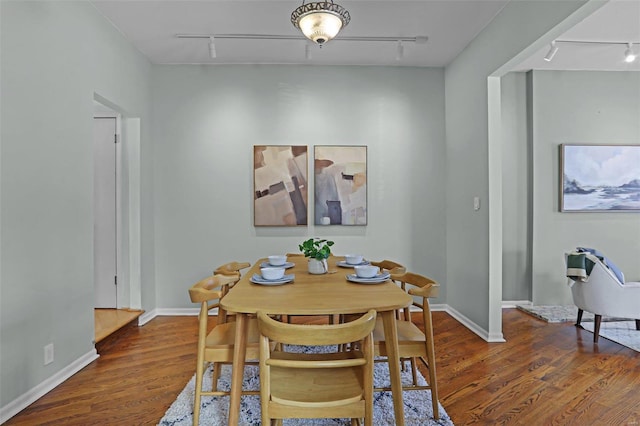 dining area with rail lighting and dark hardwood / wood-style floors