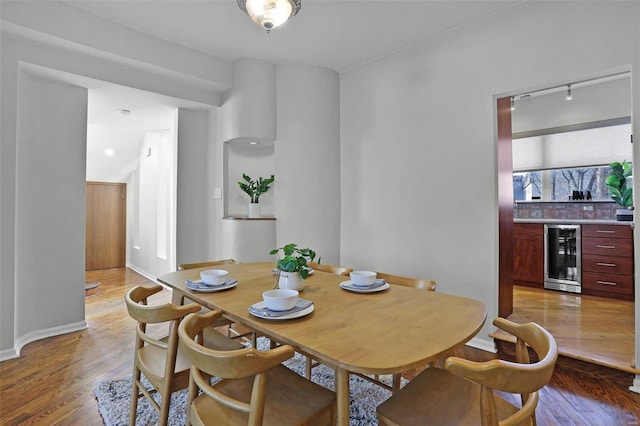 dining space featuring beverage cooler and light wood-type flooring