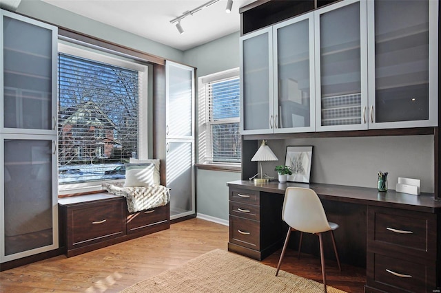 office area with rail lighting, built in desk, and light hardwood / wood-style flooring