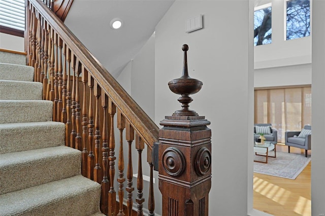 stairs with wood-type flooring, a wealth of natural light, and high vaulted ceiling