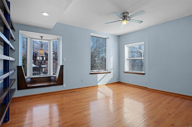 spare room with ceiling fan, a textured ceiling, and light wood-type flooring