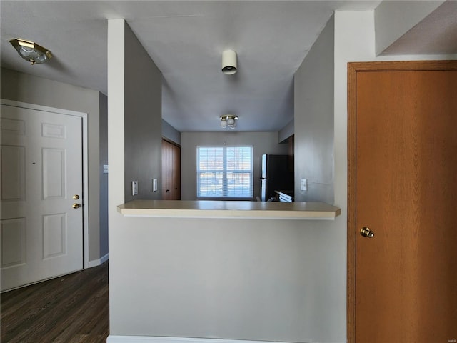 kitchen featuring kitchen peninsula, dark hardwood / wood-style flooring, and fridge