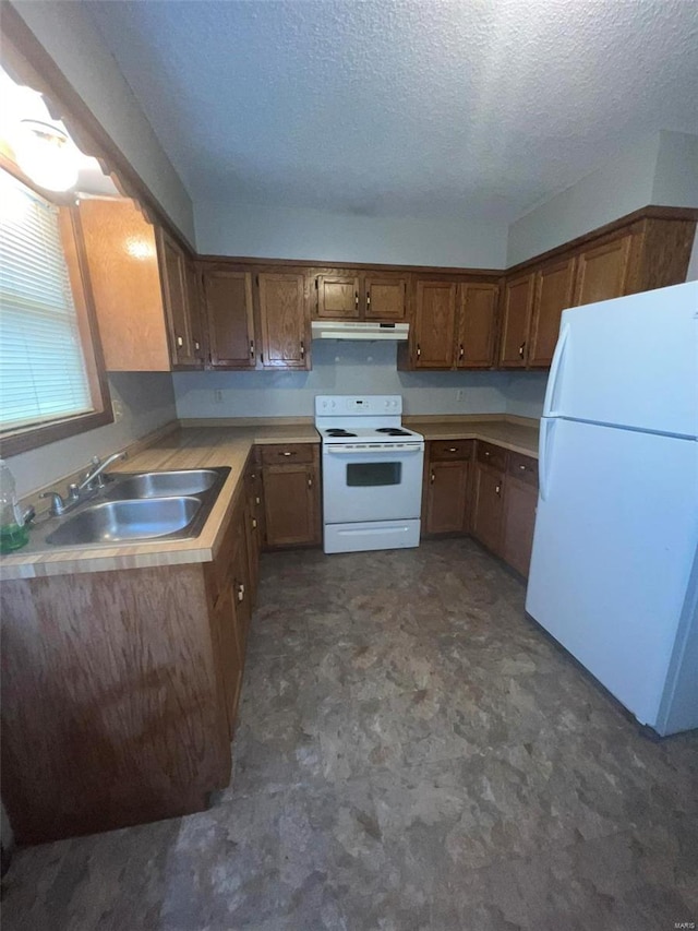 kitchen featuring a textured ceiling, white appliances, and sink