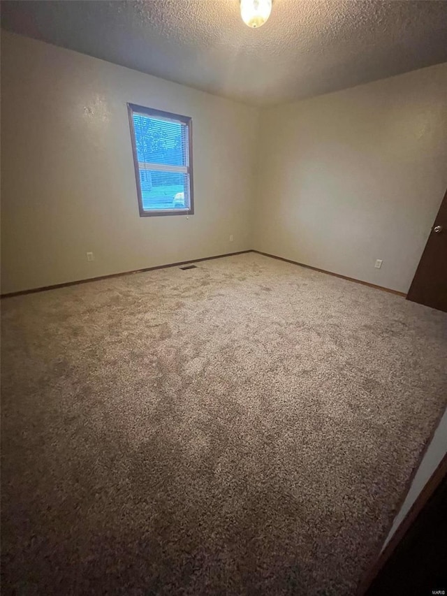 carpeted empty room with a textured ceiling