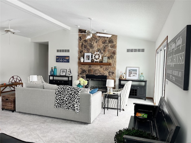 living room featuring a stone fireplace, lofted ceiling with beams, ceiling fan, carpet flooring, and a textured ceiling