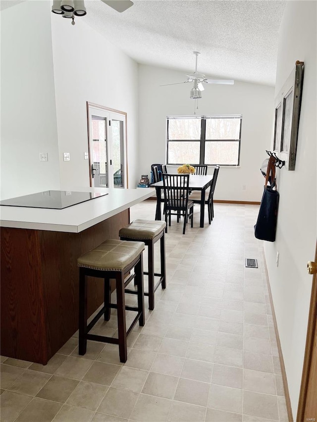 tiled dining space with a textured ceiling, ceiling fan, and vaulted ceiling