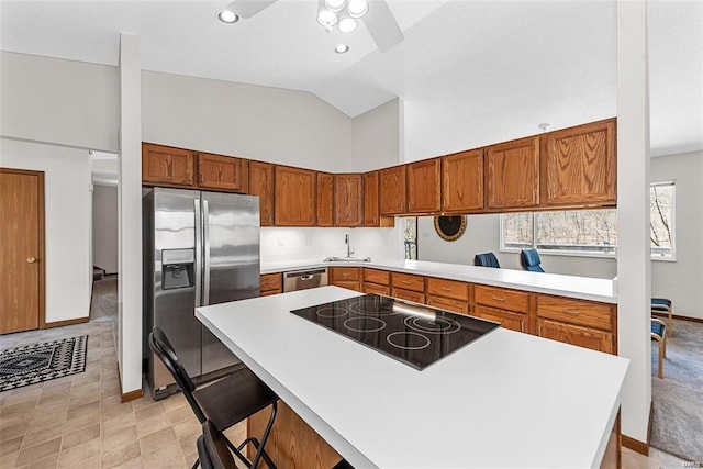 kitchen featuring a breakfast bar, high vaulted ceiling, appliances with stainless steel finishes, ceiling fan, and sink