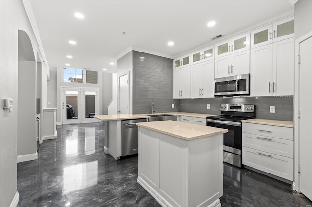 kitchen with stainless steel appliances, a kitchen island, white cabinetry, and sink