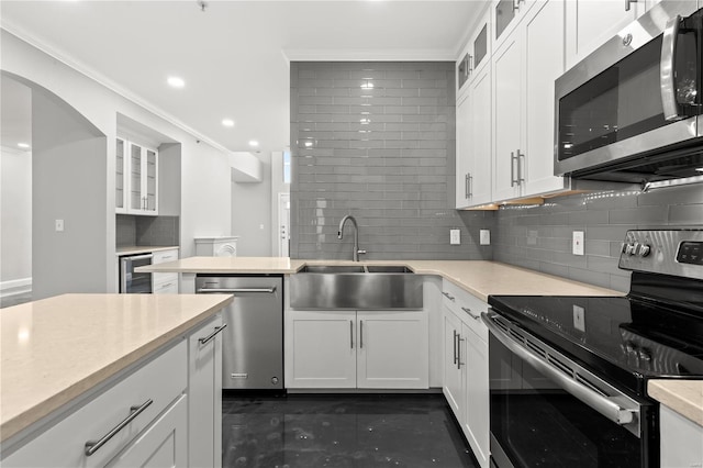 kitchen with backsplash, sink, white cabinets, and appliances with stainless steel finishes