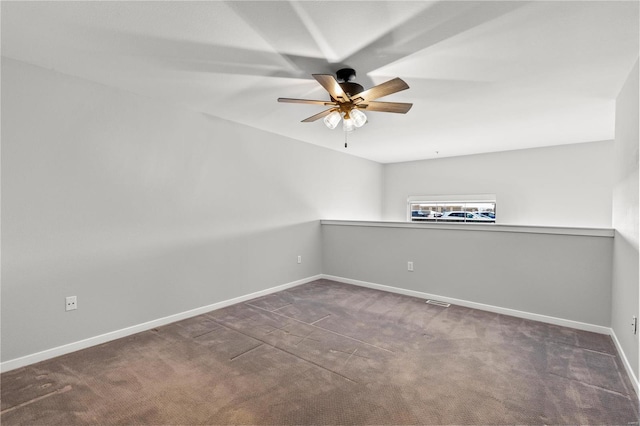 spare room featuring dark colored carpet and ceiling fan