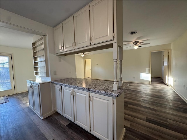 kitchen with white cabinets, ceiling fan, kitchen peninsula, stone countertops, and dark wood-type flooring