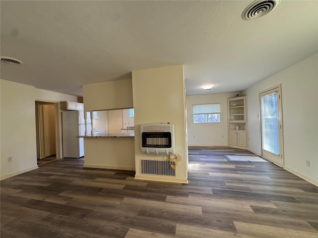 kitchen with dark wood-type flooring, white fridge, heating unit, and kitchen peninsula