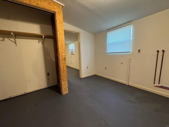 unfurnished bedroom with lofted ceiling, a textured ceiling, and a closet