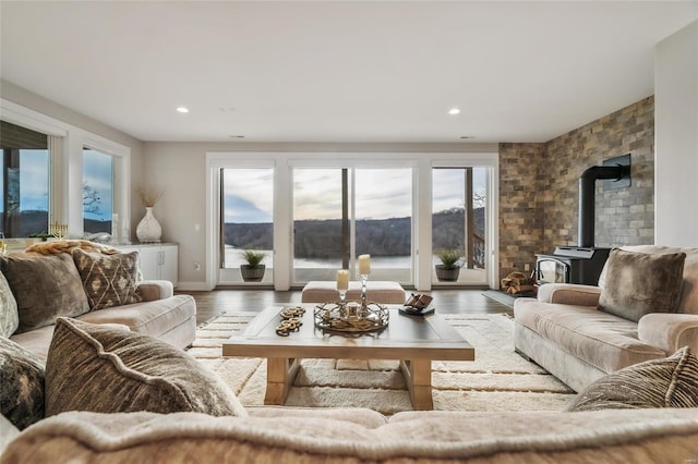 living room featuring a wood stove, a wealth of natural light, a water view, and hardwood / wood-style flooring