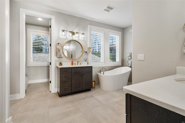 bathroom with a washtub, vanity, and tile patterned flooring