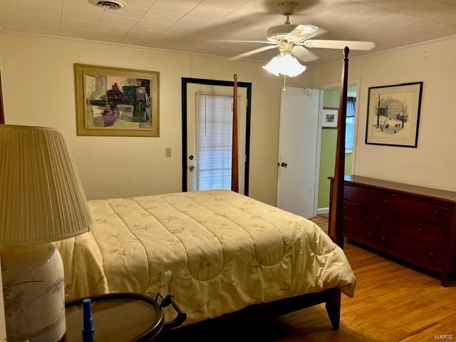 bedroom featuring hardwood / wood-style flooring, ceiling fan, and ornamental molding