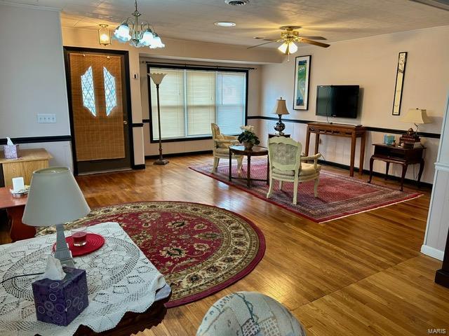 interior space featuring hardwood / wood-style floors and ceiling fan with notable chandelier